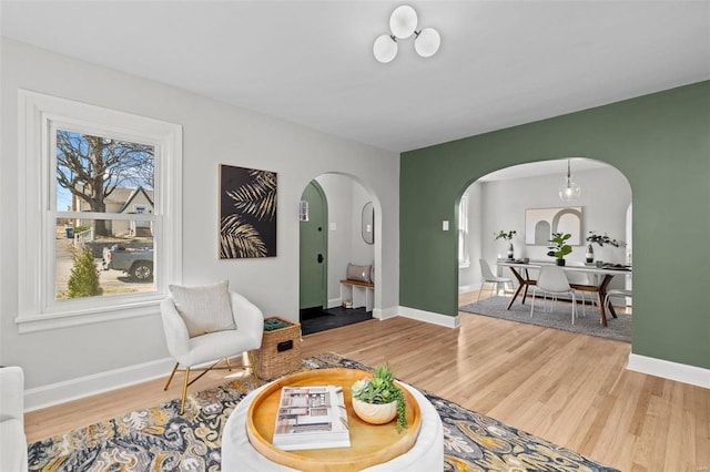 sitting room with baseboards, arched walkways, and wood finished floors