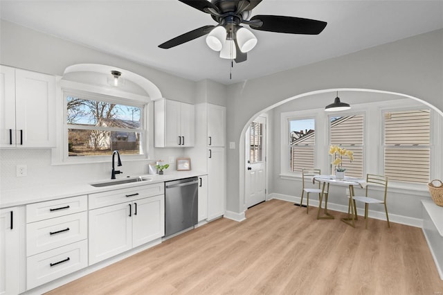 kitchen with tasteful backsplash, light countertops, stainless steel dishwasher, light wood-style floors, and a sink