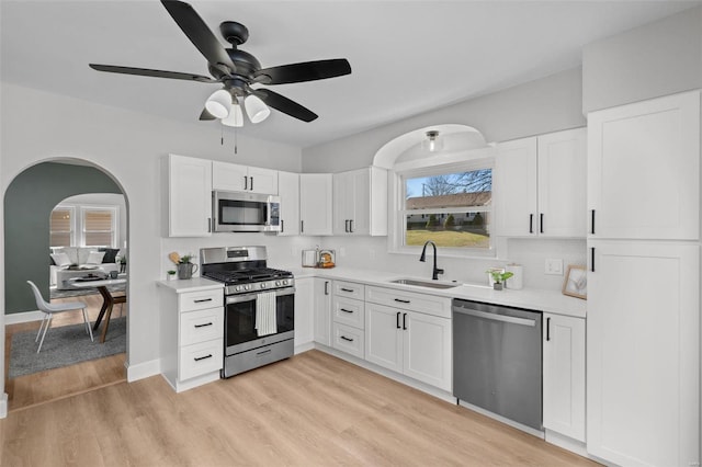 kitchen with a sink, light countertops, light wood-style flooring, and stainless steel appliances