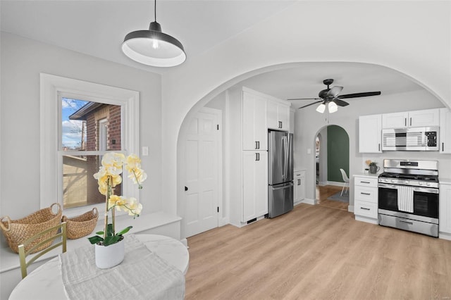 kitchen with decorative light fixtures, light wood-type flooring, light countertops, white cabinets, and stainless steel appliances