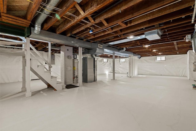 basement featuring electric panel, stairway, gas water heater, and visible vents