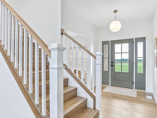 foyer entrance with stairway, visible vents, and light wood finished floors