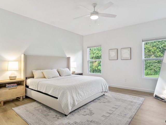 bedroom featuring baseboards, light wood-style flooring, and a ceiling fan