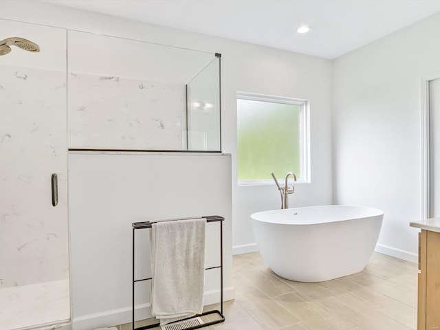 bathroom with a soaking tub, baseboards, and a stall shower