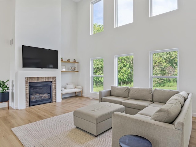 living area with a brick fireplace, baseboards, and wood finished floors