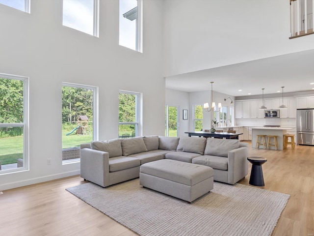 living area featuring recessed lighting, light wood-style floors, baseboards, and a chandelier