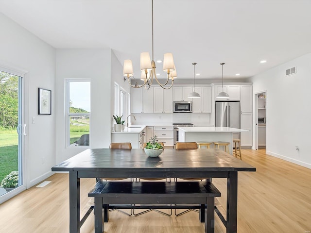 dining area with light wood finished floors, visible vents, and a healthy amount of sunlight