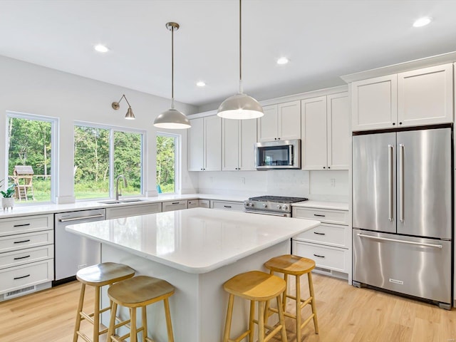 kitchen with a sink, stainless steel appliances, a kitchen breakfast bar, and visible vents