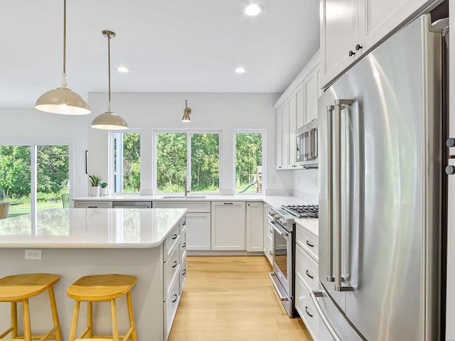 kitchen with high quality appliances, light wood-type flooring, light countertops, recessed lighting, and a sink