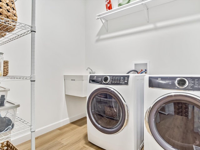 laundry area with washer and dryer, light wood-type flooring, baseboards, and laundry area