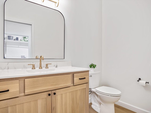 bathroom featuring baseboards, toilet, wood finished floors, and vanity