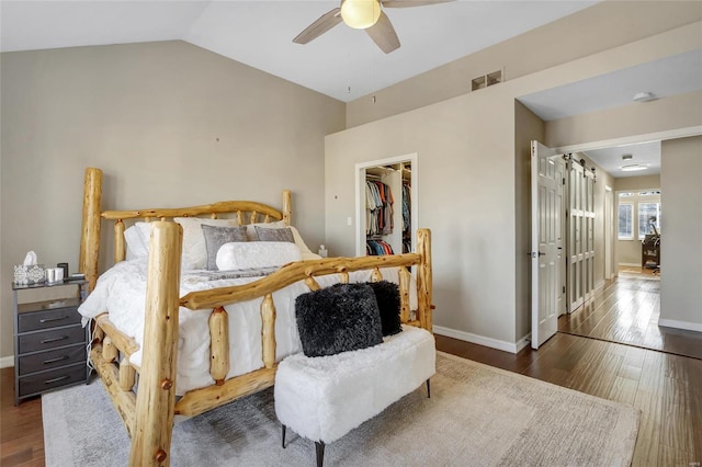 bedroom with visible vents, wood finished floors, a spacious closet, and vaulted ceiling