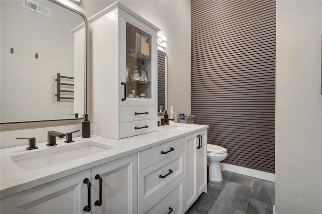 full bath featuring double vanity, visible vents, toilet, and a sink