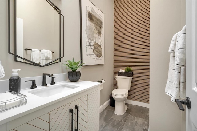 bathroom featuring toilet, vanity, and baseboards