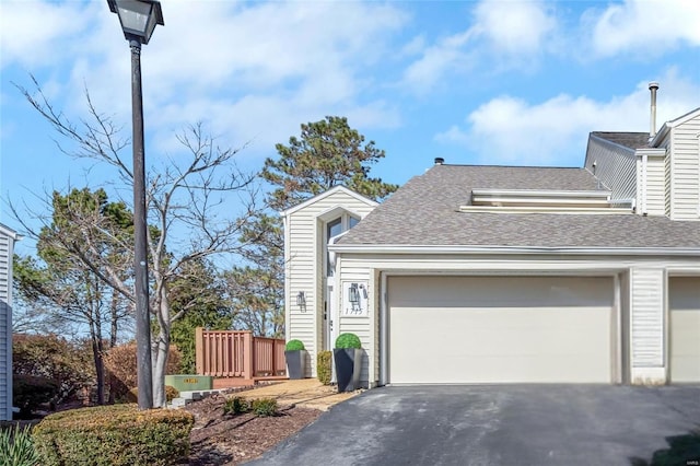 view of front of house featuring aphalt driveway, a garage, and a shingled roof