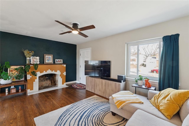 living room with a fireplace with flush hearth, baseboards, a ceiling fan, and wood finished floors