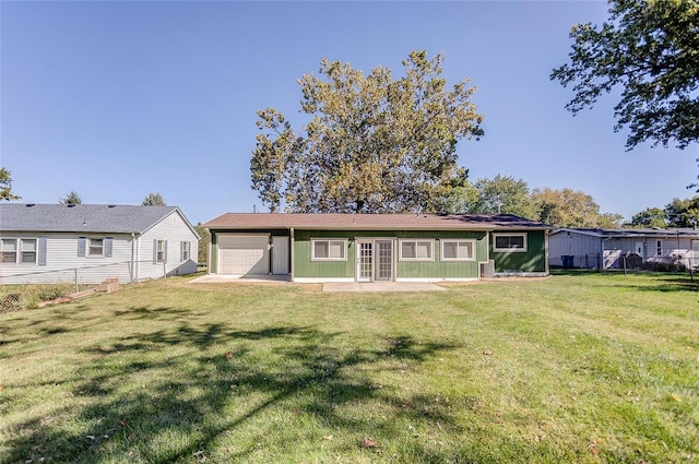 back of property with a yard, a garage, and fence