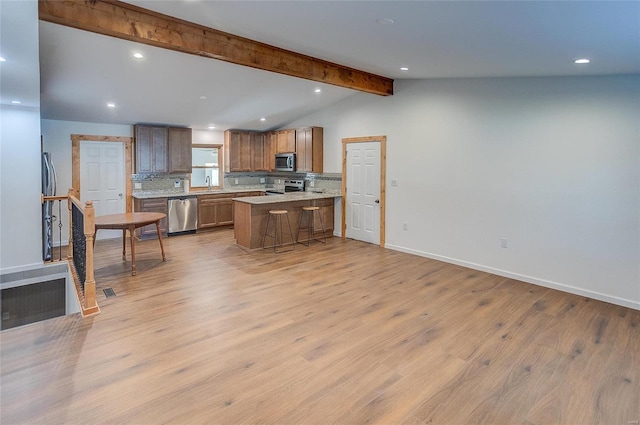 kitchen featuring tasteful backsplash, light countertops, light wood-style floors, stainless steel appliances, and a sink