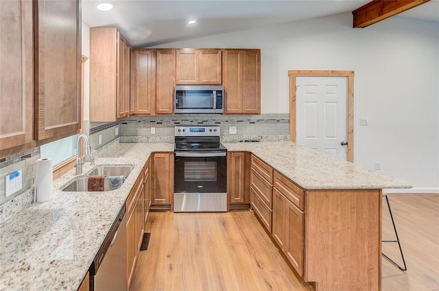 kitchen featuring a peninsula, vaulted ceiling with beams, a sink, stainless steel appliances, and a kitchen bar