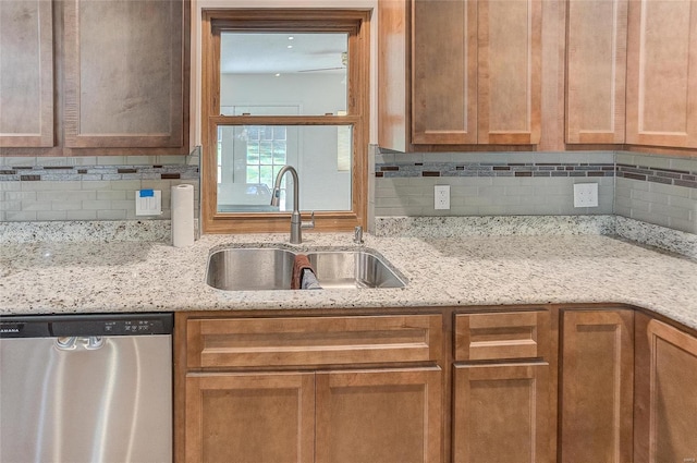 kitchen featuring stainless steel dishwasher, decorative backsplash, light stone countertops, and a sink