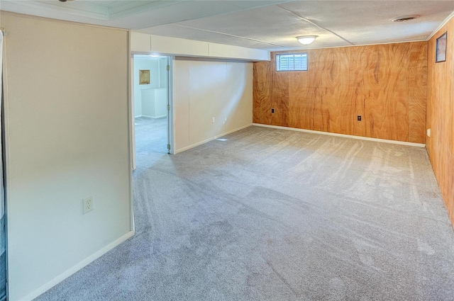 basement with baseboards, carpet floors, wooden walls, and visible vents