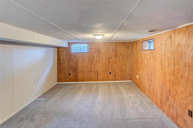 basement with visible vents, carpet floors, a textured ceiling, and wood walls