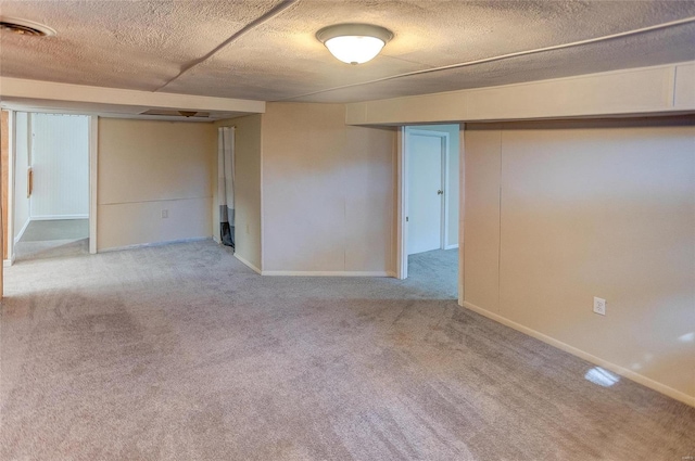 carpeted spare room featuring baseboards and a textured ceiling