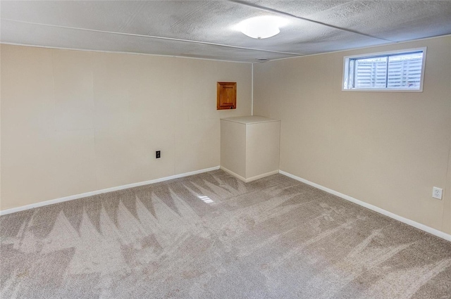 basement featuring light carpet, a textured ceiling, and baseboards