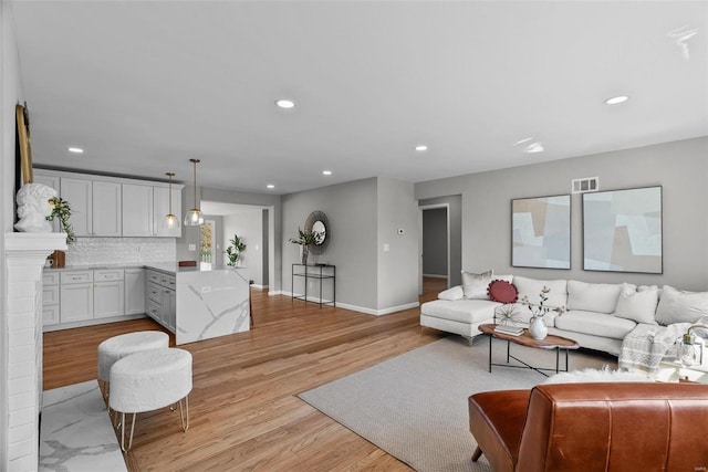 living room featuring recessed lighting, visible vents, baseboards, and light wood-style flooring