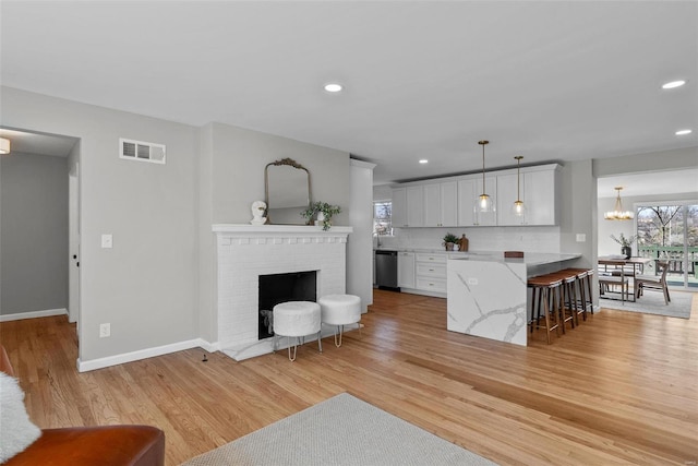 living room with baseboards, visible vents, recessed lighting, a fireplace, and light wood-type flooring