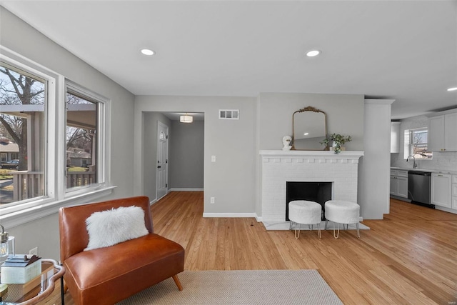 living area featuring visible vents, recessed lighting, a fireplace, and light wood-type flooring