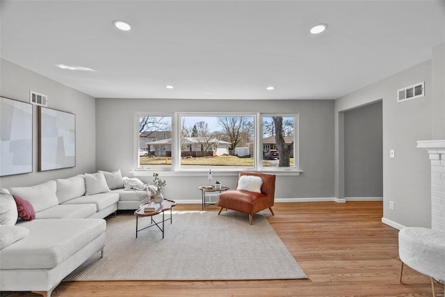 living room with visible vents, a fireplace, baseboards, and wood finished floors