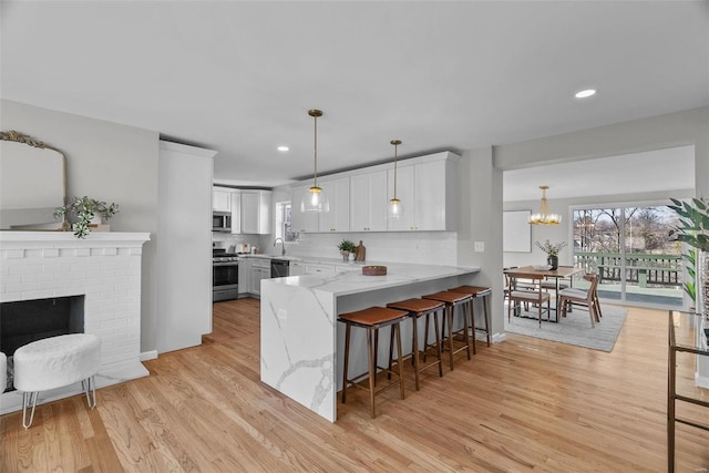 kitchen featuring light stone countertops, a peninsula, appliances with stainless steel finishes, a kitchen breakfast bar, and backsplash