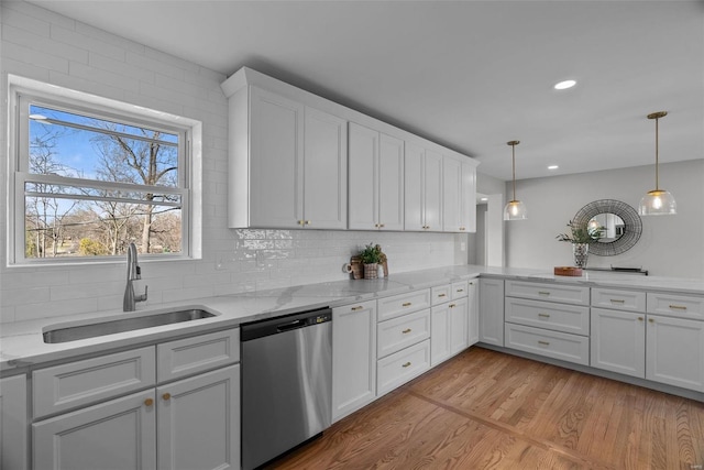 kitchen featuring a sink, tasteful backsplash, white cabinetry, light wood-style floors, and dishwasher