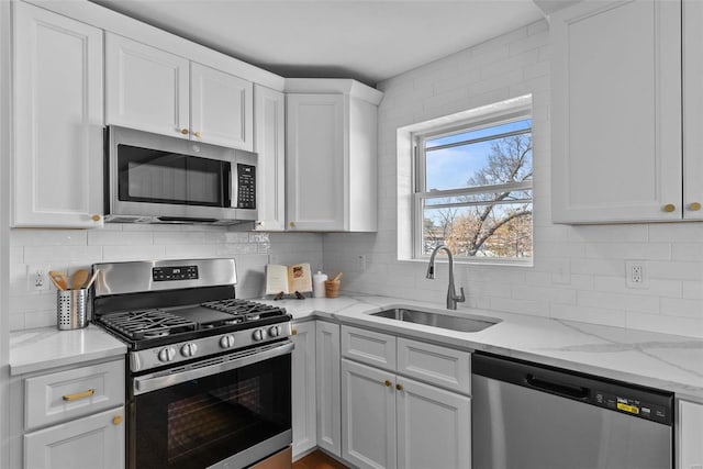 kitchen with a sink, backsplash, appliances with stainless steel finishes, and white cabinets