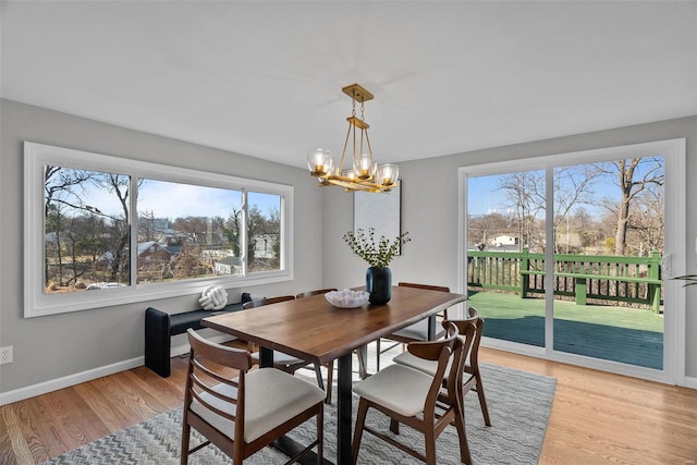 dining space featuring light wood-type flooring, baseboards, and a chandelier