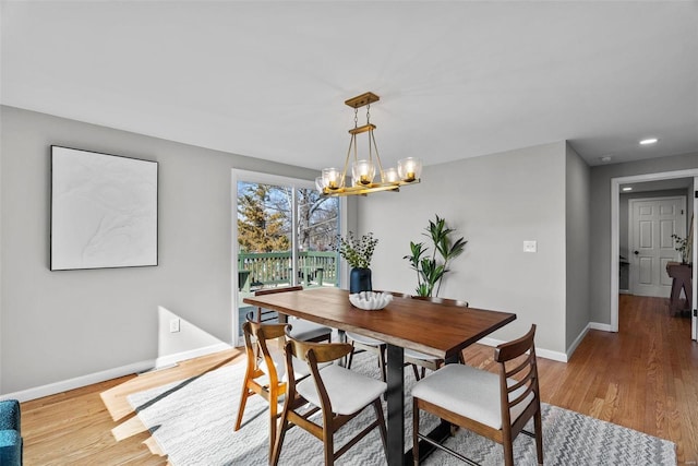 dining area with baseboards, a notable chandelier, and wood finished floors