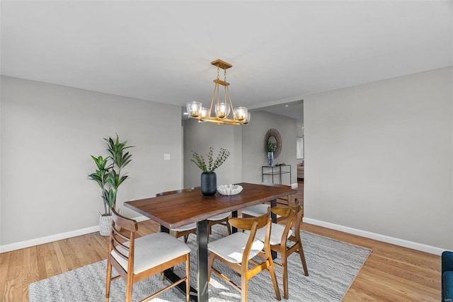 dining area with baseboards, light wood-type flooring, and a chandelier