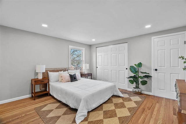 bedroom with recessed lighting, baseboards, light wood-type flooring, and a closet