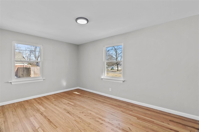 unfurnished room with baseboards, a healthy amount of sunlight, and wood finished floors