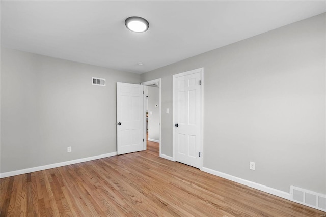 spare room with light wood finished floors, visible vents, and baseboards