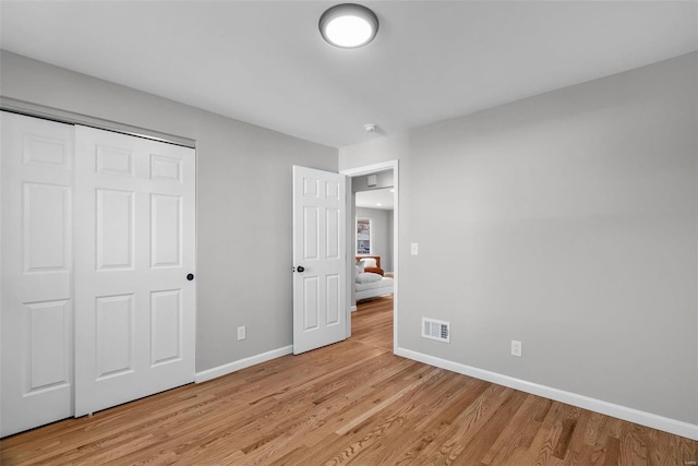 unfurnished bedroom with baseboards, visible vents, a closet, and light wood-type flooring