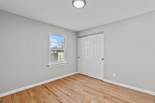 unfurnished bedroom with a closet, light wood-type flooring, and baseboards