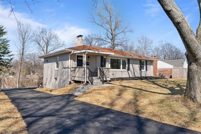 view of front of house featuring stucco siding, fence, and a chimney