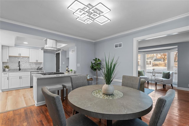 dining space with visible vents, baseboards, crown molding, and light wood finished floors