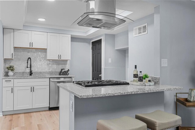 kitchen with visible vents, extractor fan, a kitchen bar, white cabinets, and stainless steel dishwasher