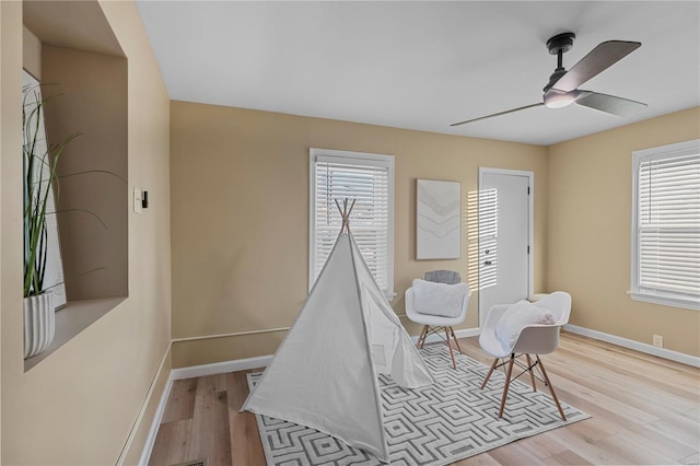 game room featuring baseboards, light wood-style floors, and a ceiling fan