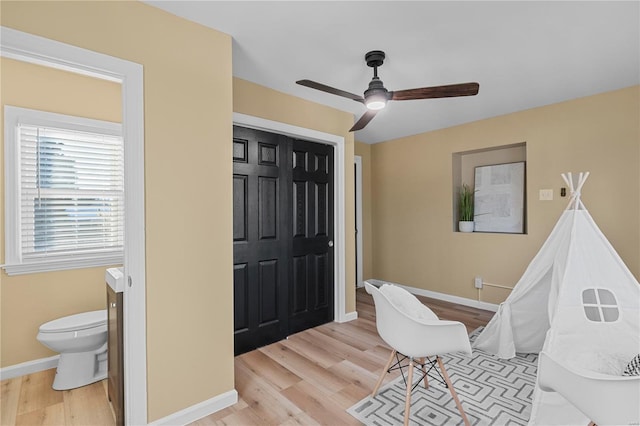 interior space with a ceiling fan, light wood-style floors, and baseboards