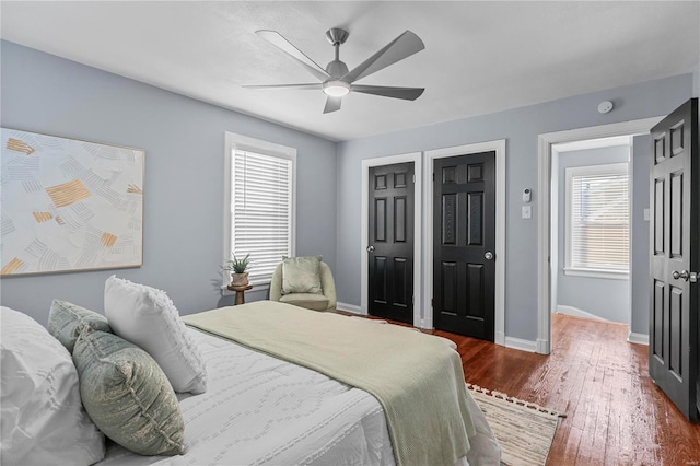 bedroom featuring a ceiling fan, dark wood-style floors, and baseboards
