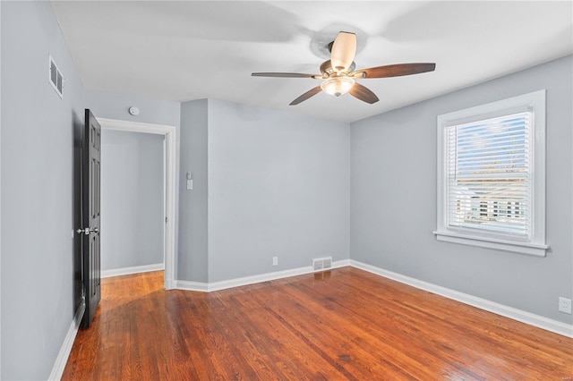 spare room featuring visible vents, baseboards, and wood finished floors